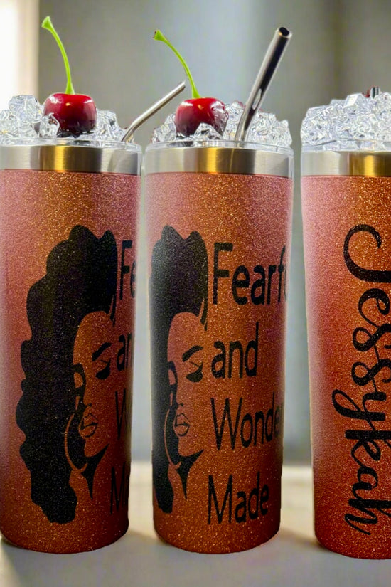 Three glittery orange Kreative Kreationz Custom 20oz Tumblers with ice, cherries, reusable metal straws, and 3D lid toppers. Two feature an illustrated woman with “Fearfully and Wonderfully Made”; the third says “Jessykah.”.