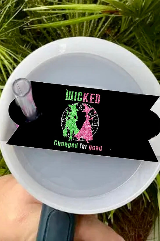 A hand holds a white cup with the Kreative Kreationz Wicked - Stanley Lid Topper and a black straw tag saying 
