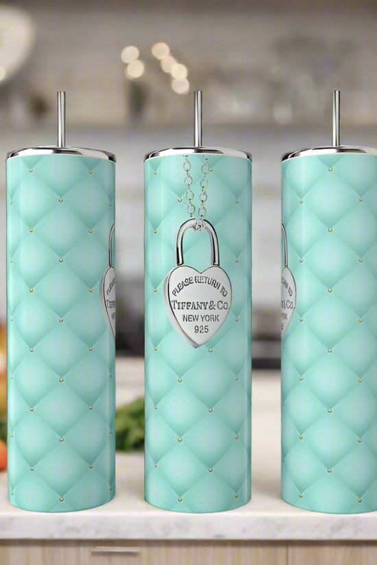 Three tall, light blue Kreative Kreationz Tiffany Locket 20oz Tumblers with quilted patterns and silver lids and straws stand on a kitchen counter. Each features a silver heart emblem reading 