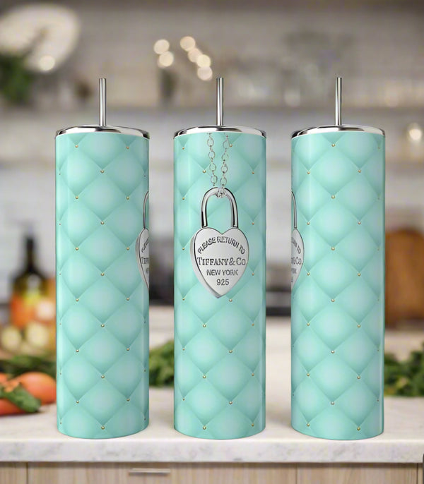 Three tall, light blue Kreative Kreationz Tiffany Locket 20oz Tumblers with quilted patterns and silver lids and straws stand on a kitchen counter. Each features a silver heart emblem reading "Please Return To Tiffany & Co. New York 925.