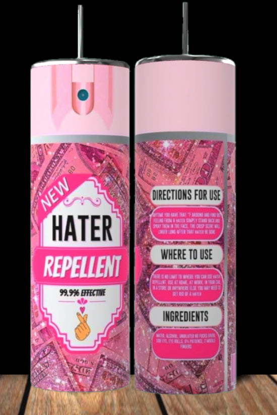 Two pink Hater Repellent 20oz Tumblers by Kreative Kreationz, featuring glitter and money graphics, stand on a wooden surface against a black background. Inspired by the playful tumbler trend, each has directions and ingredients on the back.