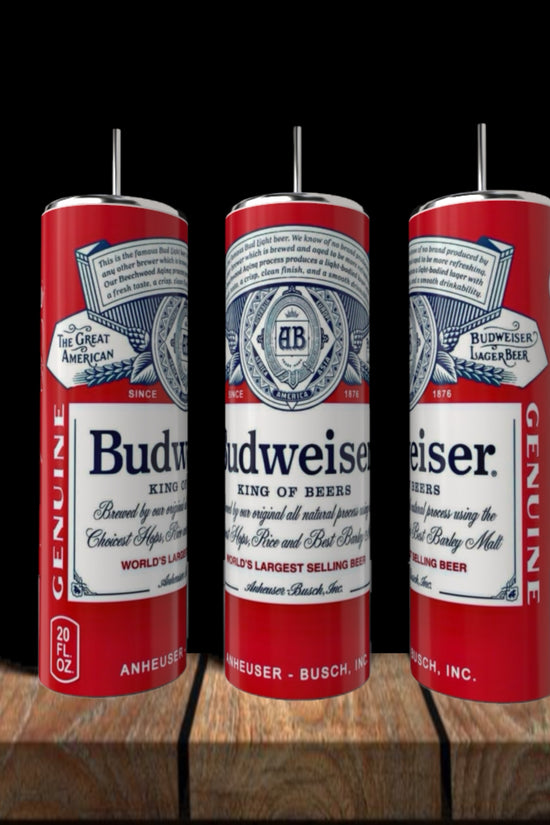 Three Budweiser 20oz Stainless Steel Tumblers by Kreative Kreationz with straws sit on a wooden surface against a black background, each featuring the classic Budweiser label and red, white, and blue design.