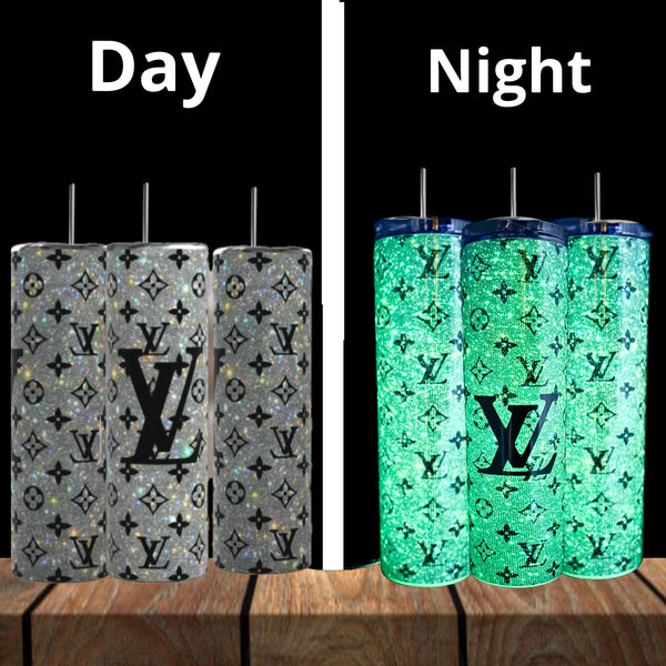 Four Kreative Kreationz Louis Vuitton GLOW IN THE DARK Shimmer 20oz Tumblers sit on wood; by day (left) they look gray and glittery, by night (right) they glow bright green. "Day" and "Night" labels appear above.