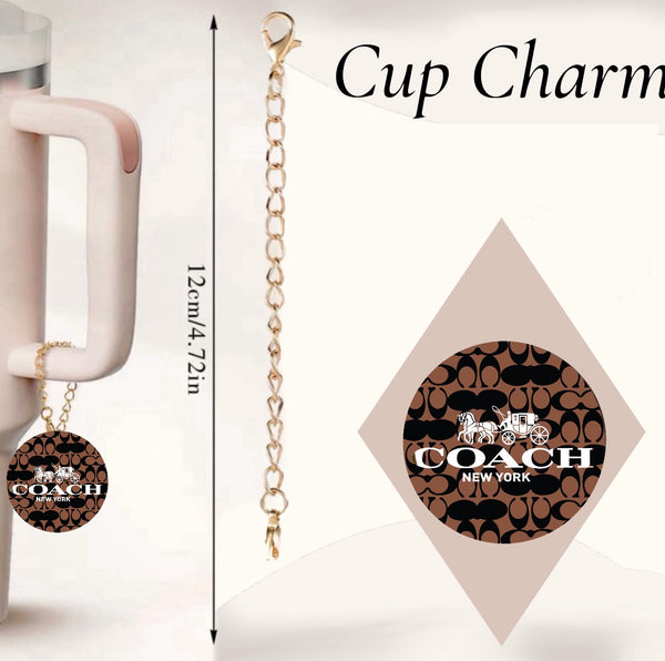 A white mug with a light pink handle from Kreative Kreationz features the Coach Cup Charm. The charm, boasting a brown and black pattern alongside the Coach New York logo, elegantly dangles as a tumbler accessory. A close-up of this handcrafted charm is shown on the right.