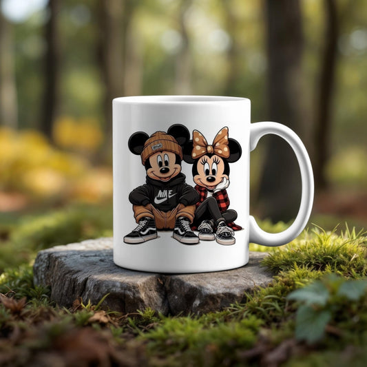 The 11oz Ceramic Mug by Kreative Kreationz showcases cartoon characters styled as Mickey and Minnie Mouse in trendy streetwear, sitting side by side. This dishwasher-safe mug is pictured outdoors on a tree stump with a blurred forest background.