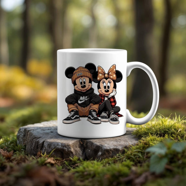 The 11oz Ceramic Mug by Kreative Kreationz showcases cartoon characters styled as Mickey and Minnie Mouse in trendy streetwear, sitting side by side. This dishwasher-safe mug is pictured outdoors on a tree stump with a blurred forest background.