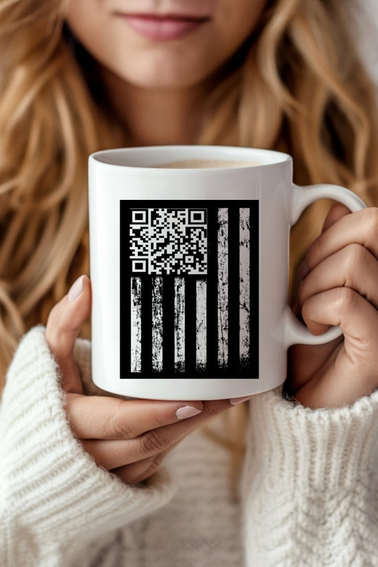 A woman with long blonde hair in a white knit sweater holds the Trump Dancing QR Code Mug by Kreative Kreationz, featuring a black American flag design with a QR code replacing the stars.