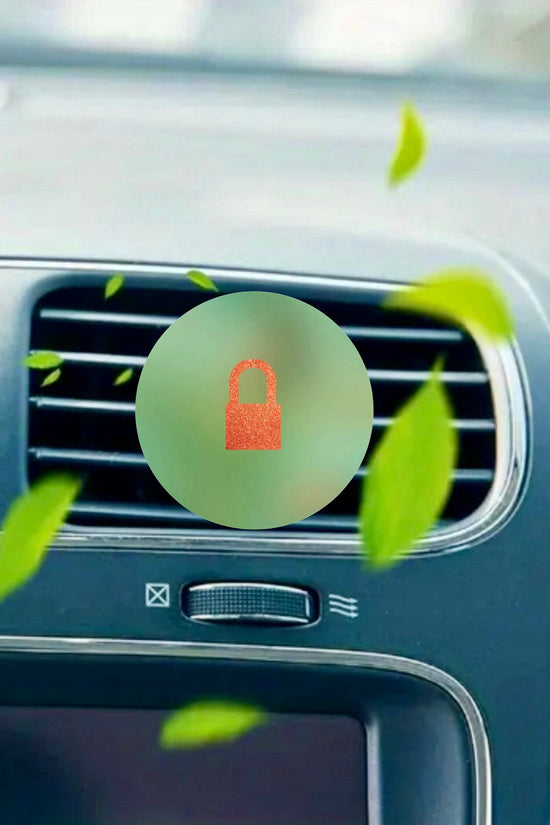 Close-up of a car dashboard air vent with green leaves and a red padlock icon, illustrating the secure and refreshing effect of the TS12 Car Air Freshener by Kreative Kreationz.