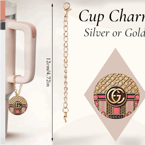 The Gucci Pink Charm Dangle by Kreative Kreationz is a 12 cm (4.72 in) cup accessory with pink and black details, shown hanging from a mug. Available in silver or gold finishes.