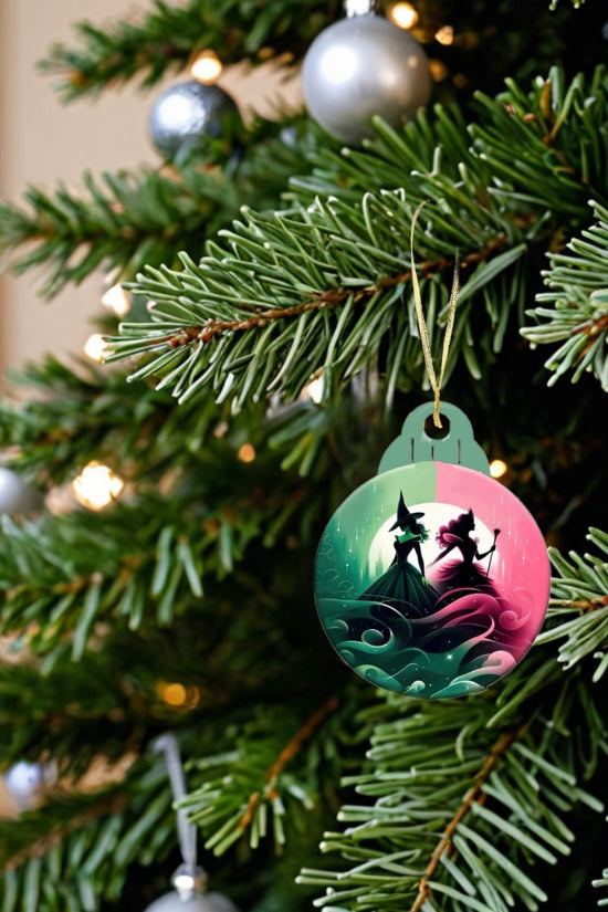 A Christmas tree adorned with silver and white ornaments shines with a festive glow, enhanced by the soft, warm lights. Among the holiday decorations is a Kreative Kreationz Wicked Christmas Tree Ornament, which features silhouettes of two dancing figures against a colorful background, crafted by festive decorators.