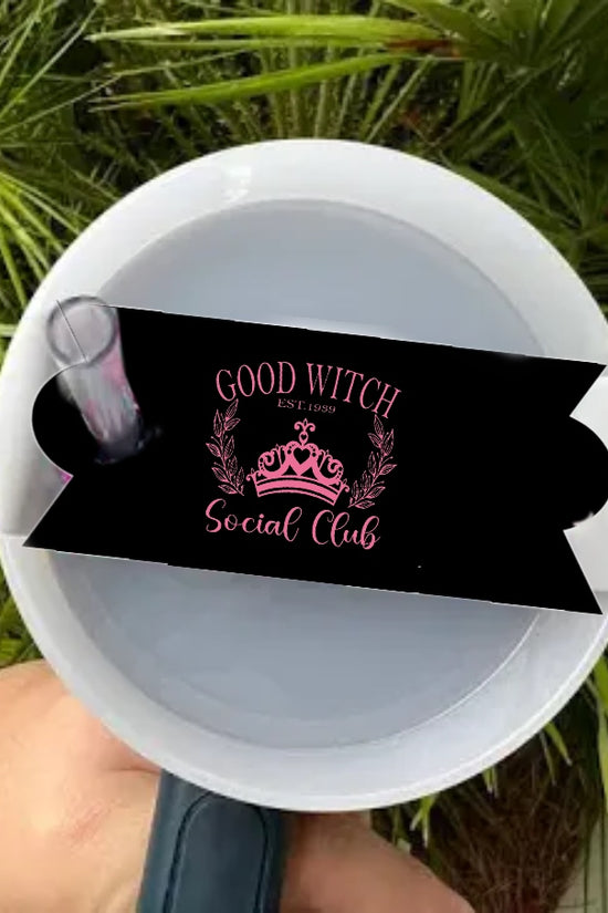 A hand holds a durable tumbler accessory from Kreative Kreationz: the Wicked | Good Witch Social Club Stanley Lid Topper, designed like a white mug with a black ribbon, pink 