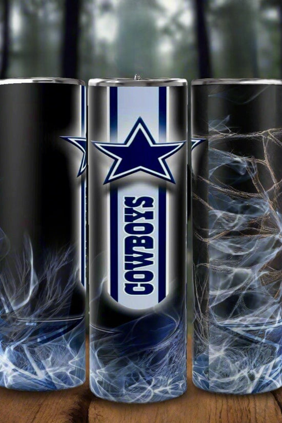 Three eco-friendly Kreative Kreationz Dallas Cowboys NFL custom 20oz skinny tumblers, featuring a smoky blue and white design with a large blue star and “COWBOYS” vertically, are shown on wood with a forest background.