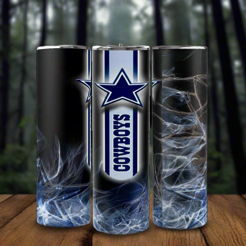 Three eco-friendly Kreative Kreationz Dallas Cowboys NFL custom 20oz skinny tumblers, featuring a smoky blue and white design with a large blue star and “COWBOYS” vertically, are shown on wood with a forest background.