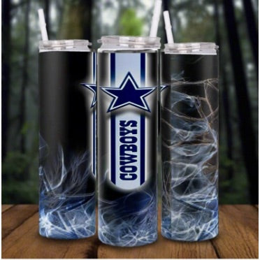 Three Kreative Kreationz Dallas Cowboys NFL Custom 20oz Skinny Tumblers with clear lids and straws, featuring the team's star logo and smoky abstract patterns, are displayed on a wooden surface with a blurred forest background.