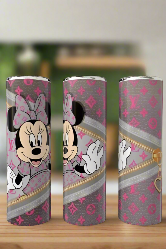 Three 20oz skinny tumblers from Kreative Kreationz’s Mickey Mouse LV Peek-a-Boo Collection, featuring grey and pink patterns, gold zippers, and Minnie Mouse designs, are displayed on wood with a blurred kitchen background.