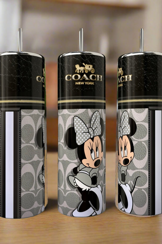 Three Kreative Kreationz 20oz skinny tumblers, including the Mickey Mouse Coach design, are displayed on a wooden table with a blurred kitchen background, showcasing stylish and luxury drinkware.
