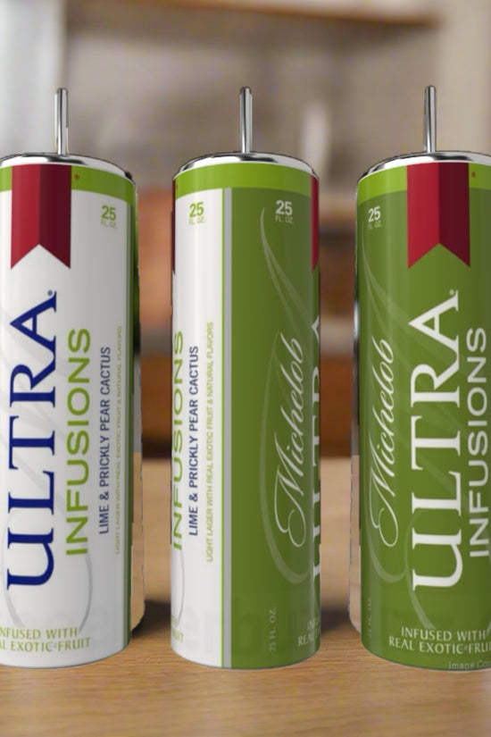 Three cans of Michelob Ultra Infusions Lime & Prickly Pear Cactus beer rest on a wooden surface beside a sleek 20oz Silver Stainless Steel Tumbler by Kreative Kreationz, perfect for enjoying your drink in style.