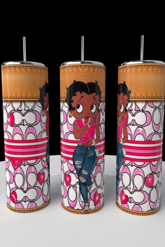 Three vibrant Kreative Kreationz Betty B Coach 20oz Skinny Tumblers, each adorned with Betty Boop in a pink shirt and ripped jeans against pink and white heart-striped patterns, are showcased with metal straws on a round white surface.