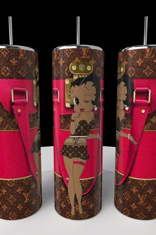 Kreative Kreationz presents three Betty B Coach 20oz Skinny Tumblers, showcasing the iconic Betty Boop in a chic outfit against a pink and brown patterned backdrop with strap details. Each sublimated tumbler includes a metallic lid and straw, displayed on a round white platform.