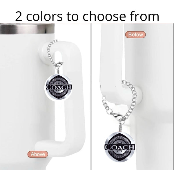 The Coach Charm Dangle by Kreative Kreationz is shown on a white mug handle, displayed above and below the handle. "2 colors to choose from" appears at the top. A unique cup accessory for any coach!.