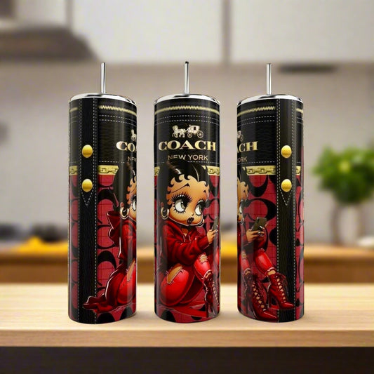 Three tall, black Kreative Kreationz Betty Boop 20oz tumblers with straws, each featuring a cartoon character in a red outfit with yellow buttons, are displayed on a counter against a blurred kitchen background.
