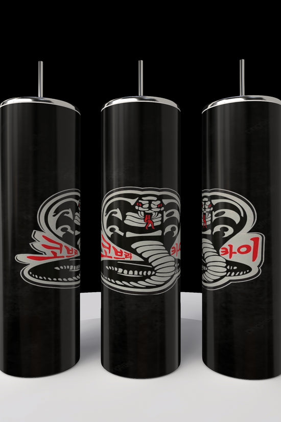 Three Kobra Kai 20oz Stainless Steel Tumblers by Kreative Kreationz, featuring a stylized cobra design and red text, stand in a row on a white circular platform against a black background.