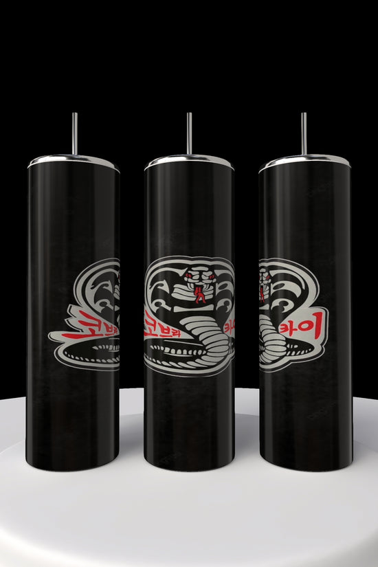 Three slender black Kobra Kai 20oz Stainless Steel Tumblers from Kreative Kreationz are displayed vertically on a circular white platform against a midnight backdrop. Each tumbler resembles spray cans with snake illustrations and red and white text, adding intrigue and elegance.