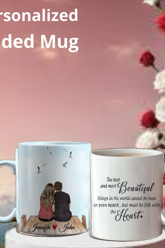 Two Kreative Kreationz Personalized Couples Ceramic Mugs against a pink and red floral background: one depicts a couple on a dock with birds, while the other showcases a romantic heart-themed quote. These mugs offer customizable options to capture your unique love story.