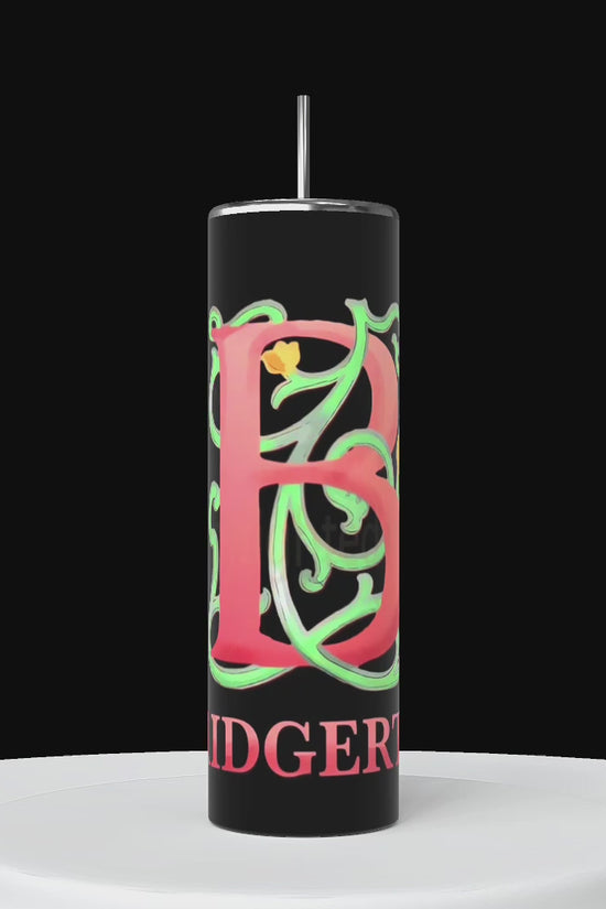 Three tall cylindrical Stanley tumblers are displayed on a white surface against a black background. Each tumbler features large, ornate letters 